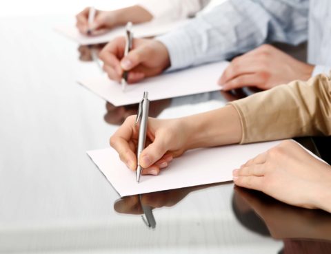 Row of writing human hands